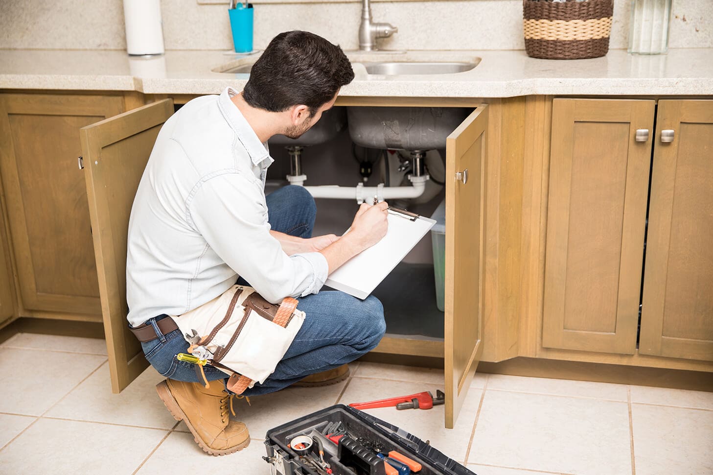 Plumber inspecting kitchen sink plumbing.