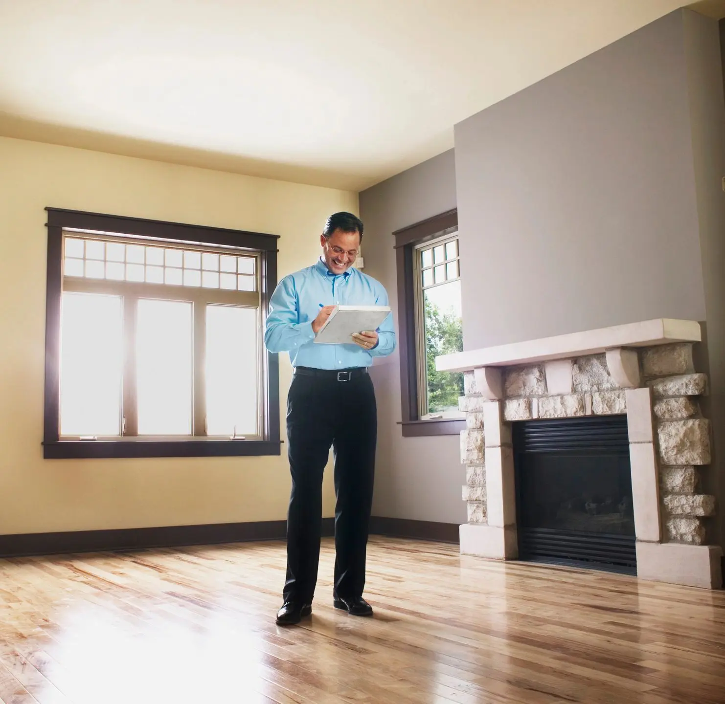 A man standing in front of a fireplace holding papers.